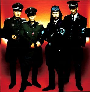 Following the release of the album WAT (Mute Records,2003), <!--LINK'" 0:170--> carried out a major European tour in 2003. Sung in both German and English WAT pondered the major topics of the Iraq War, anti-Semitism, terrorism and crisis in the modern world.