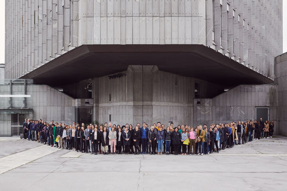 A group portrait of Biennial of Design 2019 participants, standing in front of the Central Technological Library in Ljubljana