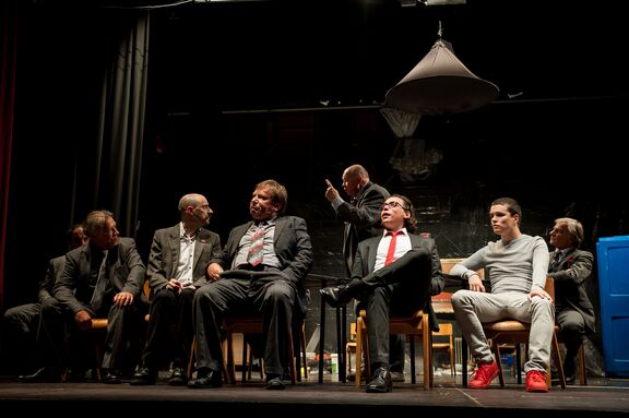 Actors Tomaž Urgl (in the back), Bojan Vister, Marko Skok, Srečko Kermavner, Tone Bertoncelj, Elias Rudolf, Jaša Levstik, and Janez Vlaj star in Reginald Rose's play 12 Angry Men. Directed by Ira Ratej and produced by Šentjakob Theatre, the play won the Matiček award for best overall performance at the Linhart Encounter in 2019. Author: Matej Maček